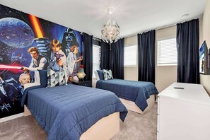Quarto com duas camas, um candelabro, uma parede decorada com tema de Star Wars e uma televisão.