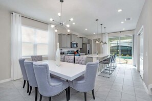 Una cocina moderna con armarios grises, una isla central y una zona de comedor con sillas tapizadas en gris.