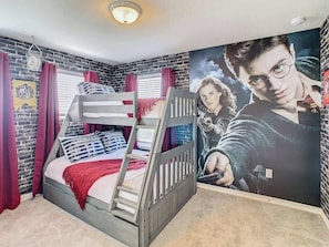 A bedroom with a bunk bed, a brick wall, a poster, and a window with curtains.