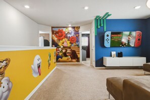 A room with a Nintendo Switch mounted on the wall, a white cabinet, and a colorful mural with Mario and other characters. - 5BD Windsor Island Private Pool  (WI 1900) (Davenport)