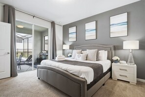 Quarto com cama grande, mesas de cabeceira, escrivaninha e vista através de uma porta de vidro.