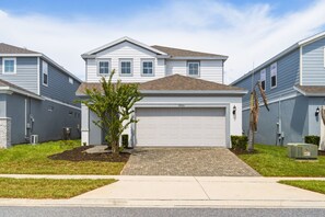 A residential building with a garage, a small tree, and a paved driveway. - 5BD Windsor Island Private Pool  (WI 1900) (Davenport)