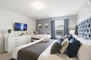 A modern hotel room with a large bed, a smaller bed, a TV, a desk, and a window with curtains. - 5BD Windsor Island Private Pool  (WI 1900) (Davenport)