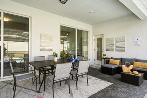 An outdoor patio with a dining table and chairs, a sofa, and a small table with decorative items. - 5BD Windsor Island Private Pool  (WI 1900) (Davenport)