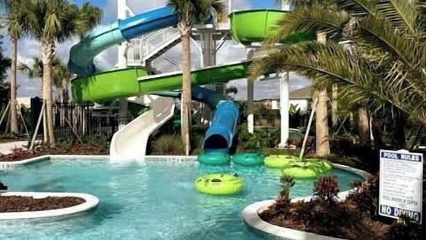 Ein Wasserpark mit Rutschen und Schwimmbecken, Palmen und einem Schild mit Poolregeln.