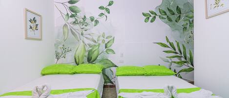 Habitación de hotel con dos camas, cada una con ropa de cama verde y toallas blancas.