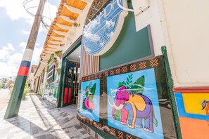 A hotel facade with colorful murals, a prominent circular sign, and a tiled walkway. - Nómada Hotel Guatapé (Guatapé)