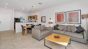 A modern living room with a sofa, coffee table, and dining area.
