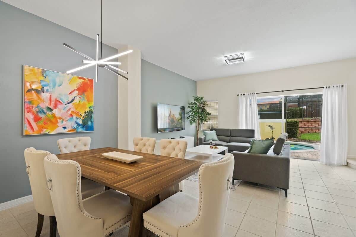 A modern living room with a dining area, a TV, and a view of the outdoors.