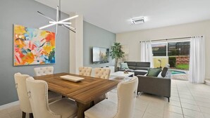 Een moderne woonkamer met een eethoek, een televisie en uitzicht op de omgeving.