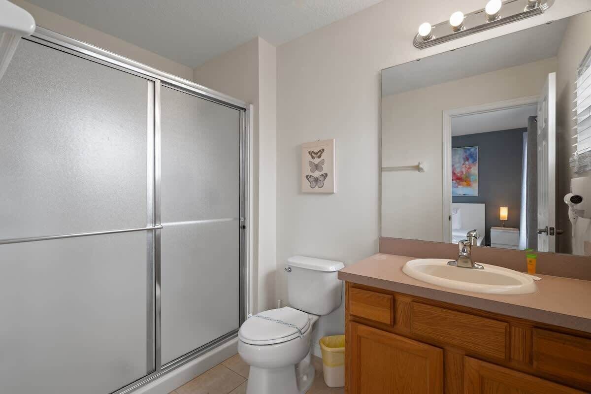 Une salle de bain comprenant des toilettes, un lavabo, un meuble-lavabo et une douche.