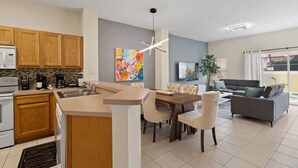 Een moderne keuken met houten kasten, een ingebouwde magnetron en een eethoek met een houten tafel en stoelen.