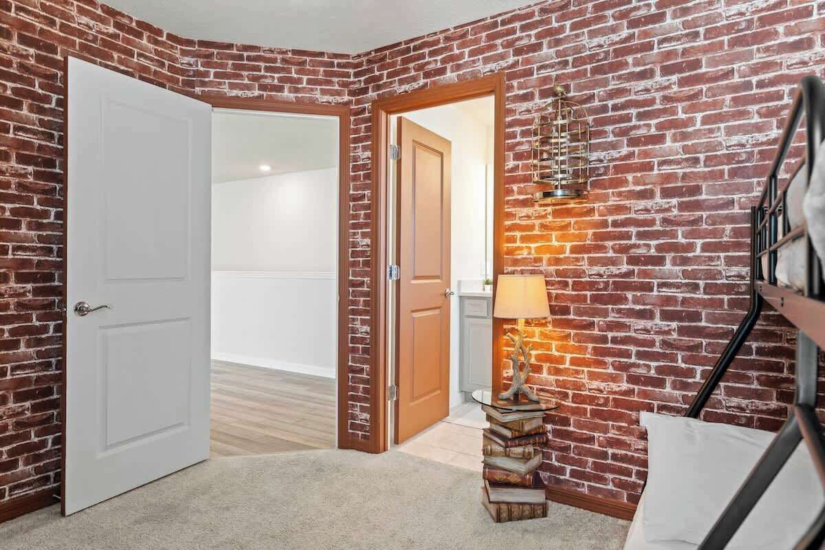 Ein Zimmer mit Ziegelwand, einer weißen Tür, einer Lampe und einem Bücherstapel.