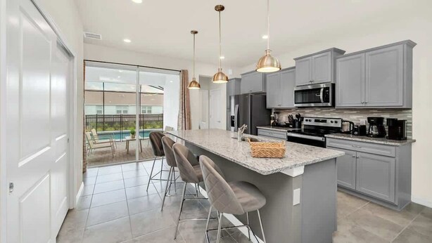 Una cocina moderna con armarios grises, electrodomésticos de acero inoxidable y una isla grande con taburetes de bar.