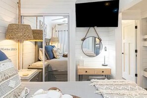 A modern bedroom with a bed, bedside lamps, a mirror, and a TV mounted on the wall. - TWO Minute Walk to the Beach-Family Friendly Oceanside Resort-King Bed (Hilton Head Island)
