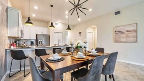A modern kitchen with white cabinets, a central island, and pendant lighting.