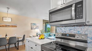 Una cocina moderna con microondas de acero inoxidable, horno y una isla grande con asientos.