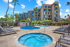 A hotel with a swimming pool, lounge chairs, and palm trees.