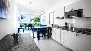 A modern kitchen with white cabinets, a granite countertop, and a built-in microwave. - Oceanfront Balcony Condo 2101 | Playa Bejuco + Sunset Views + Pool (Bejuco)