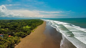 A beach with a sandy shore and a forested area. - Oceanfront Balcony Condo 2101 | Playa Bejuco + Sunset Views + Pool (Bejuco)