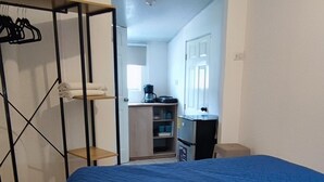 A bedroom with a large bed, a wardrobe, and a kitchenette in the background. - Comfy Stay for 2 @CasaSanAlfonso Room #21 (San Alfonso)