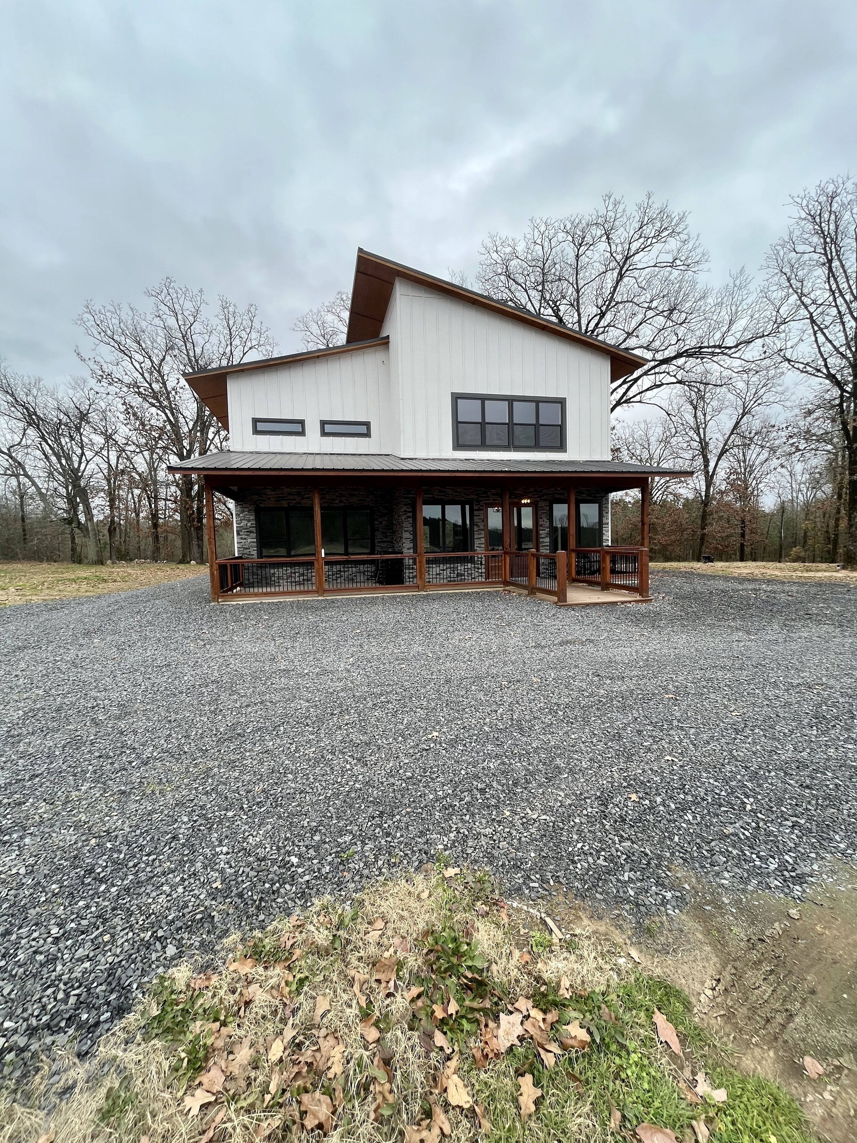 A modern two-story building with a stone foundation, large windows, and a covered porch.
