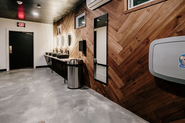 A restroom with wooden paneling, a sink with mirrors, and an exit sign.