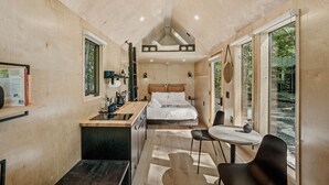Una habitación compacta y moderna con cama, un escritorio pequeño y una zona de comedor.