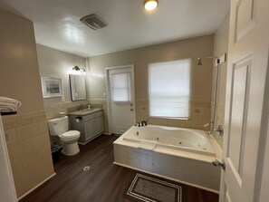 A bathroom with a toilet, sink, vanity, bathtub, and shower. - Elsinore Hot Springs & Lodge (Lake Elsinore)