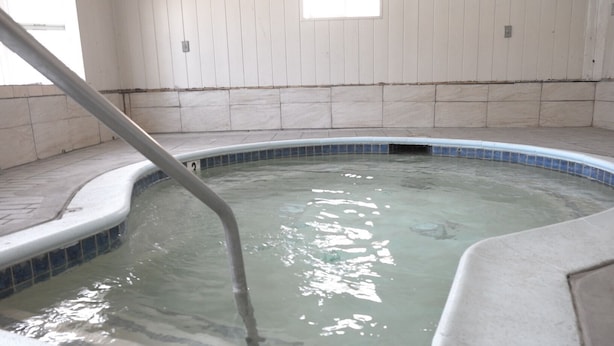 A hot tub with a tiled interior and a metal ladder. - Elsinore Hot Springs & Lodge (Lake Elsinore)