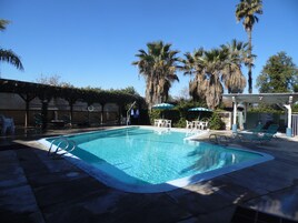 Una piscina al aire libre, sillones reclinables de piscina
