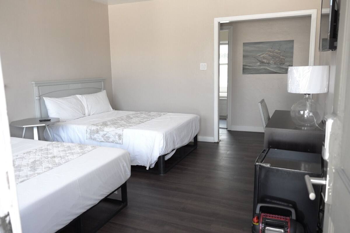 A hotel room with two beds, a desk, and a chair.
