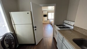 A kitchen with a refrigerator, stove, and wooden flooring. - Elsinore Hot Springs & Lodge (Lake Elsinore)
