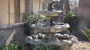 A multi-tiered stone fountain in a courtyard with a building in the background. - Elsinore Hot Springs & Lodge (Lake Elsinore)