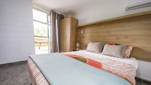 A bedroom with a bed, a wooden headboard, a nightstand, a lamp, and a window with curtains.