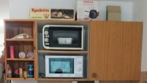 Eine kompakte Küche mit Mikrowelle, Kaffeemaschine und kleinem Kühlschrank.