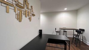 Un intérieur moderne avec un plan de travail noir, un parquet et un coin repas comprenant une table et des chaises.