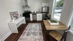 A compact kitchen with modern appliances, a dining area with a wooden table, and a view of the outdoors.