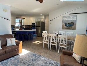 A modern kitchen with a central island, white bar stools, and a dining area with white chairs. - BRAND NEW DOCK!! New screened in porch. Peaceful cove. Close to restaurants! (Climax Springs)