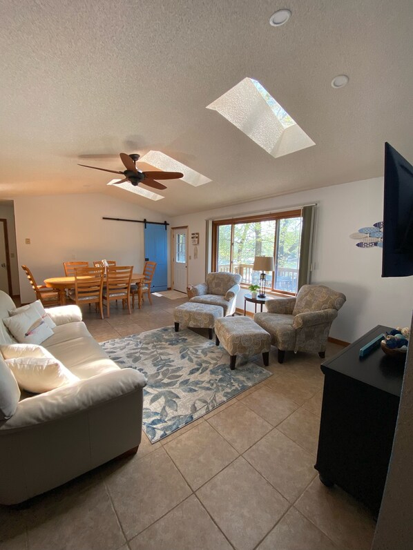 A living room with a sofa, armchairs, a coffee table, and a dining area with chairs and a table. - BRAND NEW DOCK!! New screened in porch. Peaceful cove. Close to restaurants! (Climax Springs)