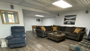 Un ampio soggiorno con soffitto alto, pavimento in legno e una grande finestra.