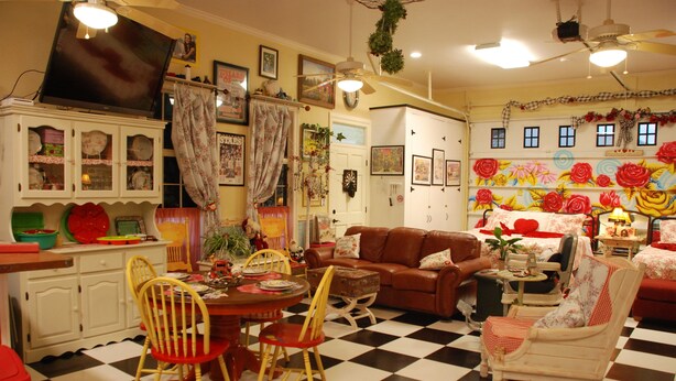 Una sala de estar acogedora con suelo de cuadros, un sofá marrón y una zona de comedor con una mesa y sillas.