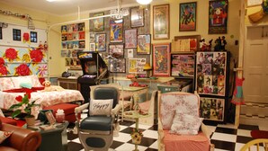Una habitación acogedora con piso a cuadros, un sillón antiguo, una mesita y una pared decorada con diversos carteles y fotografías.