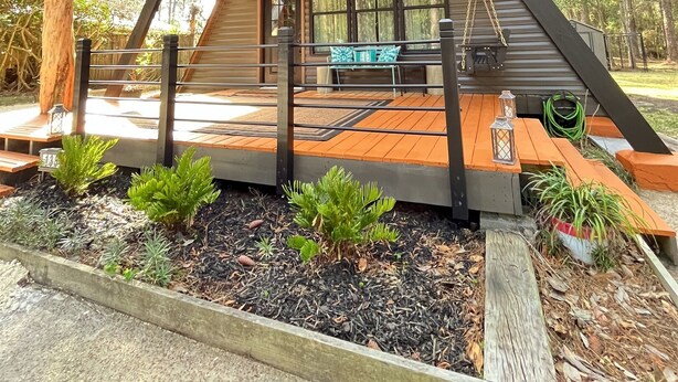 A modern, triangular wooden cabin with a balcony, surrounded by trees. - Fox Den~Perfect Escape for Birders (Dauphin Island)
