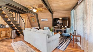 A cozy living room with a sofa, a coffee table, a fireplace, and a staircase. - Fox Den~Perfect Escape for Birders (Dauphin Island)