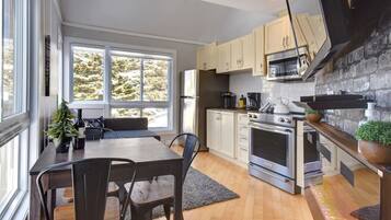 A modern kitchen with a dining area, large windows, and a stone accent wall.