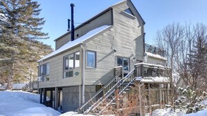 A two-story building with a balcony and a staircase leading to the entrance. - Cozy Chalet in the Mont Tremblant Ski Village (Mont-Tremblant)