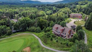 A large, two-story house with a spacious front yard and a golf course in the background.