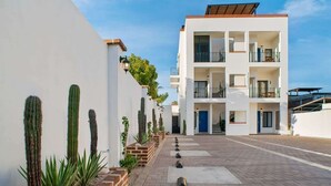 A modern multi-story building with a central courtyard, featuring a brick pathway and cacti along the walls. - Pineda Complex for Groups up to 16 Guests Downtown (La Paz)