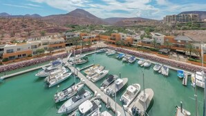 Un puerto deportivo con barcos amarrados, rodeado de edificios y un paisaje montañoso.